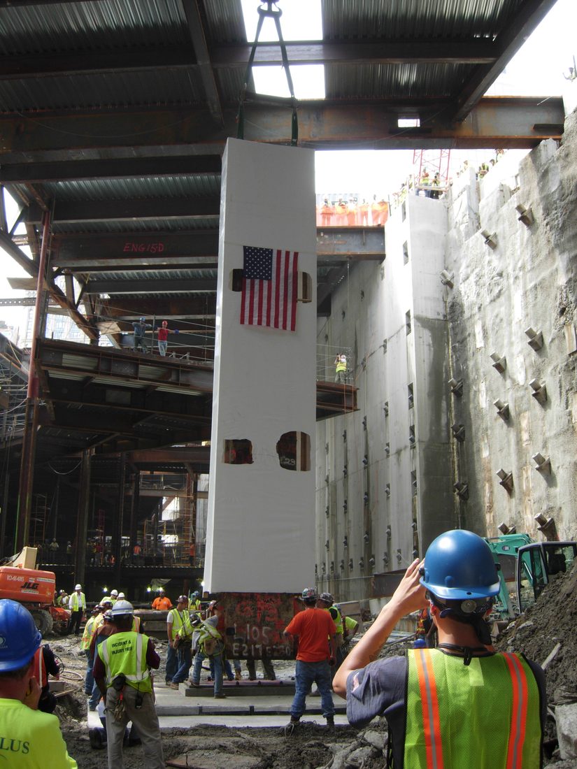 The Last Column, shrouded and flag draped, lowered back into the site